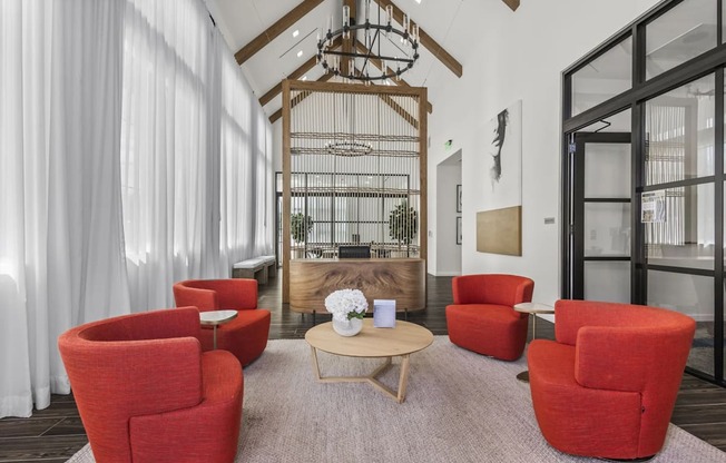 A living room with red chairs and a wooden coffee table.