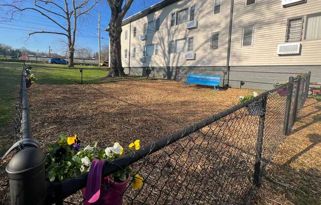 fenced dog park with flowers on the rails and a bench for people to use at The Flats at Jackson Square