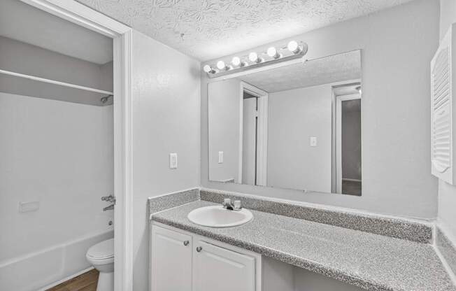 A bathroom with a sink, mirror, and lights.