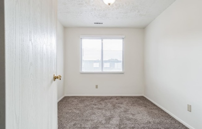 an empty bedroom with carpet and a window