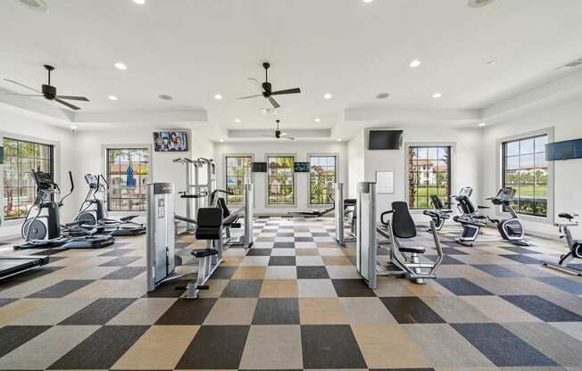 A spacious gym with a variety of exercise equipment and a checkered floor.