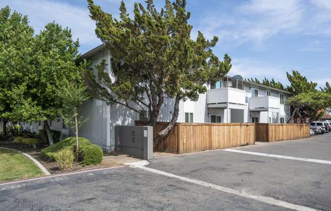 the exterior of an apartment with a wooden fence and a parking lot