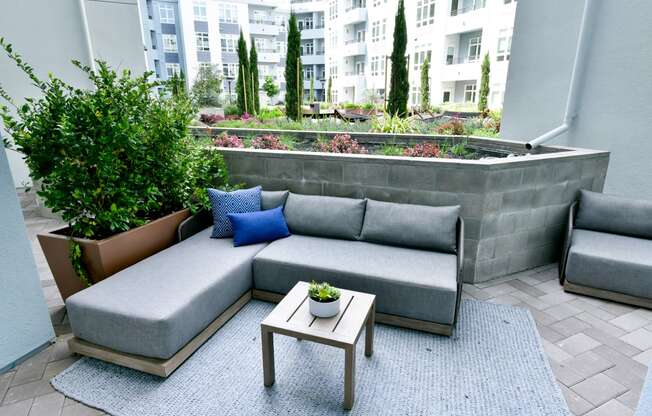 a patio with a couch and a coffee table and plants