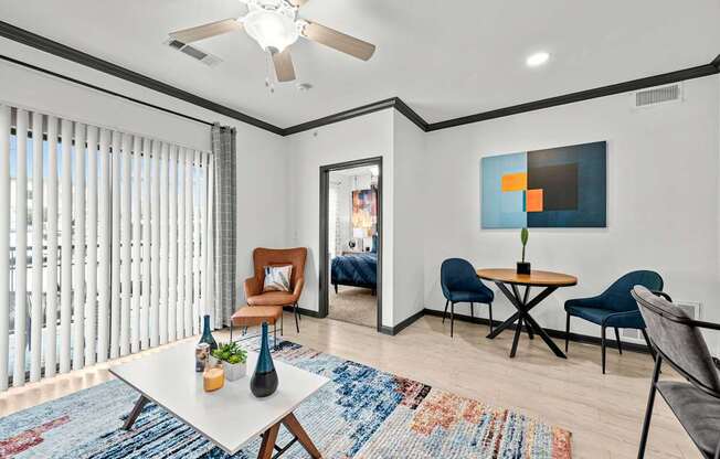 A living room with a white ceiling fan, a blue rug, and a painting on the wall.