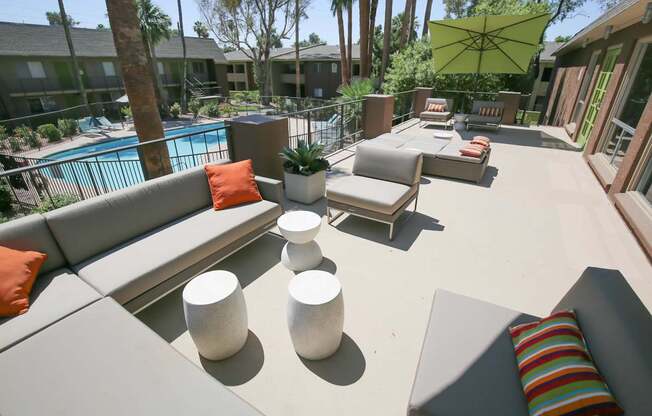 a large patio with couches and tables and a pool