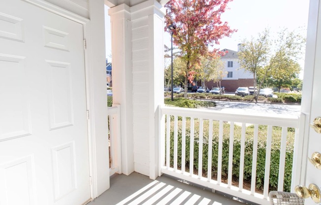 A white door is open to a balcony with a white railing.