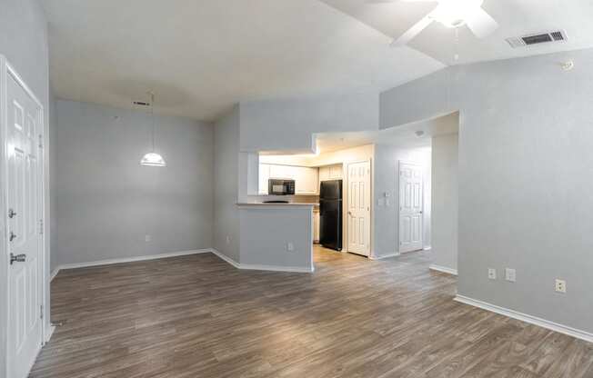 the living room and kitchen of an empty apartment with wood flooring