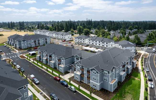 A large residential complex with multiple buildings and cars parked in front.
