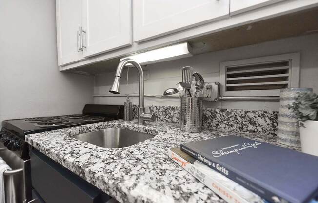 Kitchen with granite countertop, white cabinets, and stainless steel sink