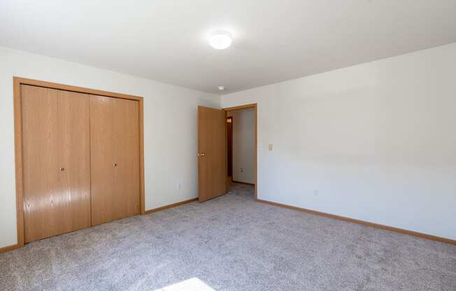 A room with two doors and carpeted floor. Fargo, ND Stonebridge Apartments
