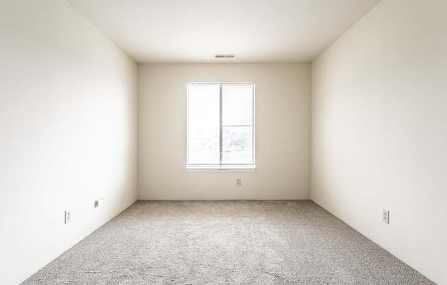 an empty room with white walls and a window