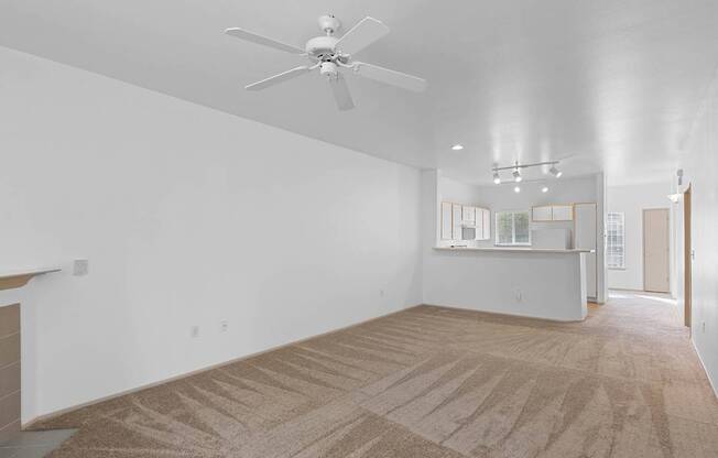 a living room with white walls and a ceiling fan