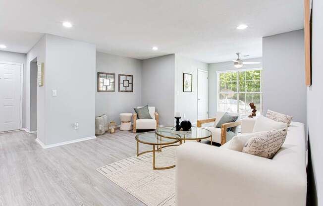 A living room with a white couch and a glass coffee table.