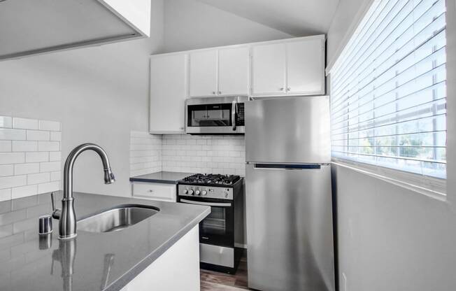 a kitchen with a sink and a stainless steel refrigerator