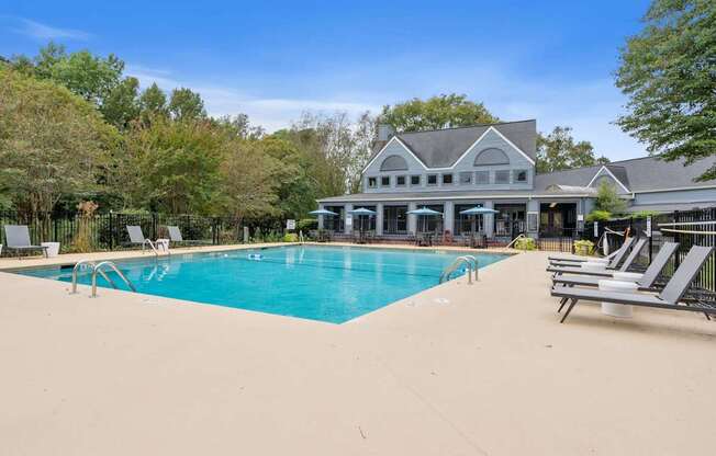 a swimming pool with chairs and a house in the background