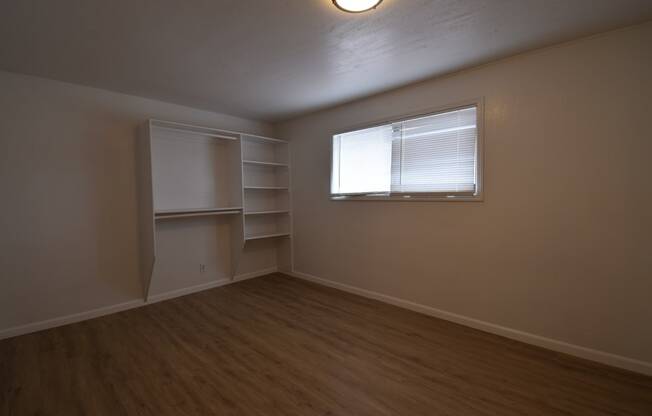 an empty living room with a window and shelves