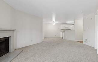 A spacious living room with a fireplace and a ceiling fan.