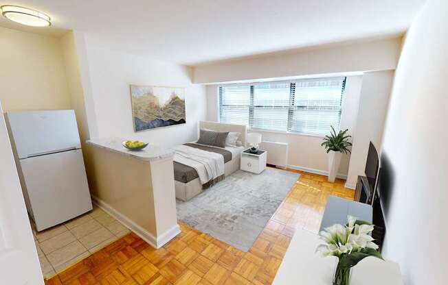 A small, well-lit apartment with a bed, a couch, and a refrigerator.