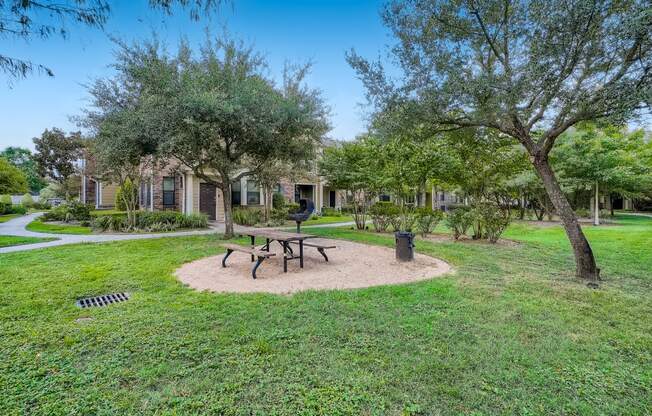 a park with a picnic table and trees in front of our apartments