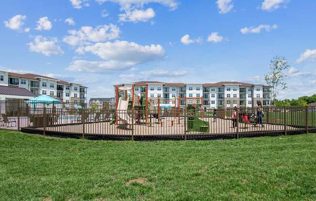 A playground with a swing set and a building in the background.