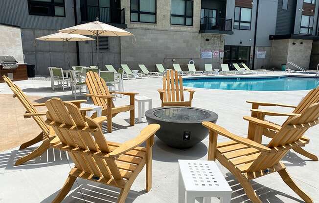 Wood Adirondack chairs arranged around a firepit near an outdoor pool at Haven at Uptown.
