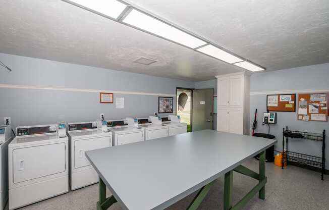 a laundry room with a table and washers and dryers