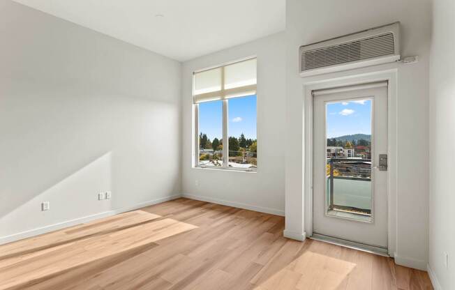A room with a wooden floor and a window overlooking a cityscape.