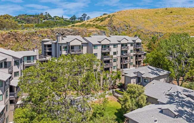 a view of the condos from above with trees and a hill