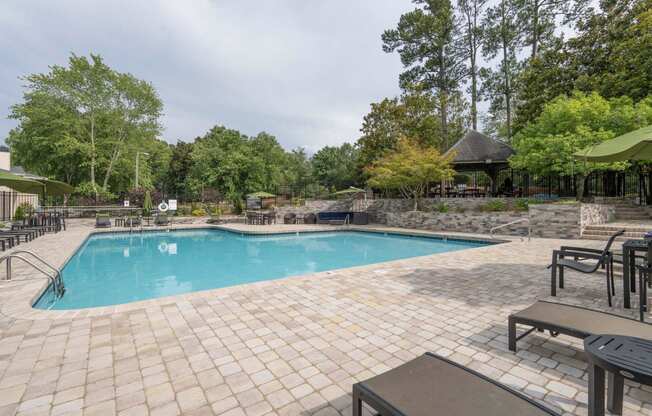 a resort style swimming pool with chairs and umbrellas