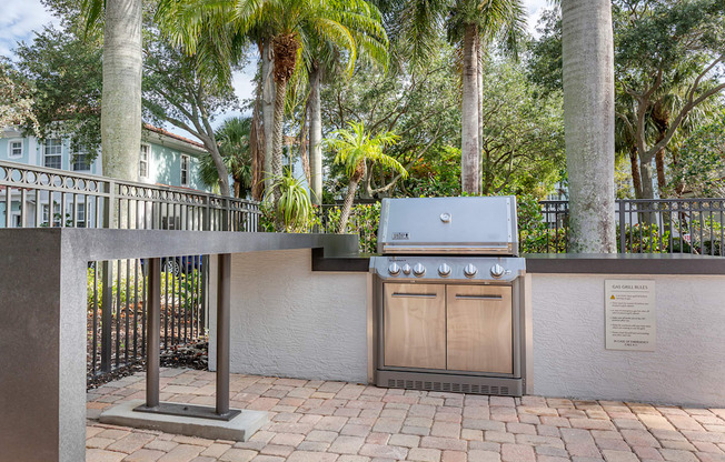 A BBQ grill is in the middle of a brick patio.