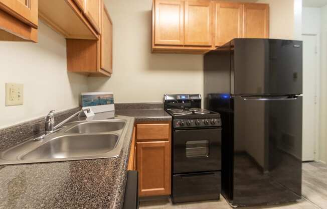 This is a photo of a kitchen with honey oak cabinets and black appliances in a 560 square foot 1, 1 bath apartment at Park Lane Apartments in Cincinnati, OH.