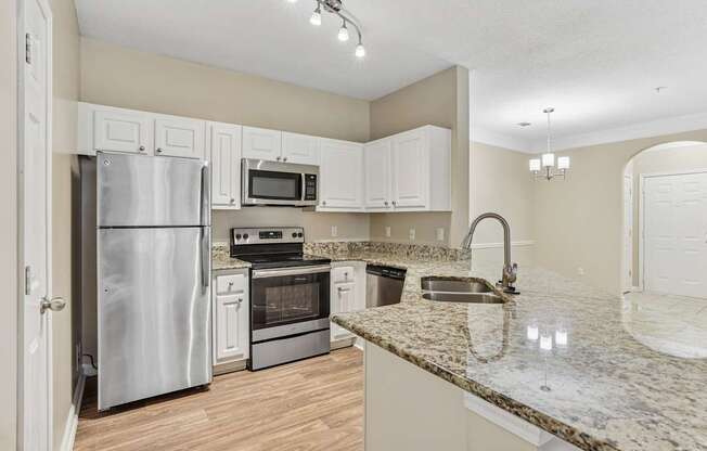 A kitchen with a granite counter top and stainless steel appliances.