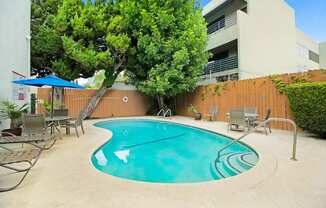 a swimming pool with chairs and umbrellas in front of a building