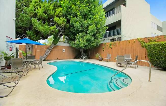 a swimming pool with chairs and umbrellas in front of a building