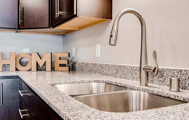 a kitchen with a sink and home letters on the counter. Circle Pines, MN Lexington Lofts