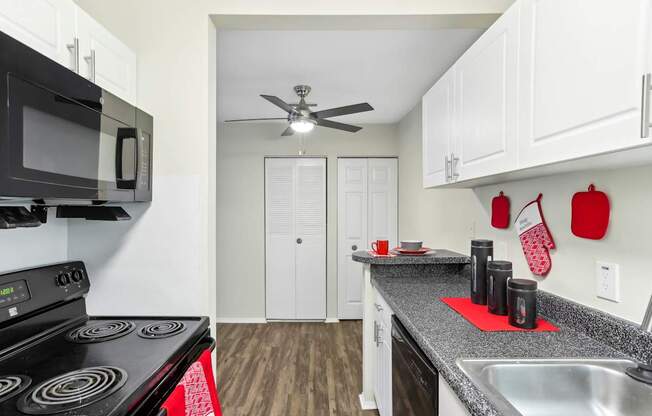 A kitchen with a black stove top oven and a black microwave above it.