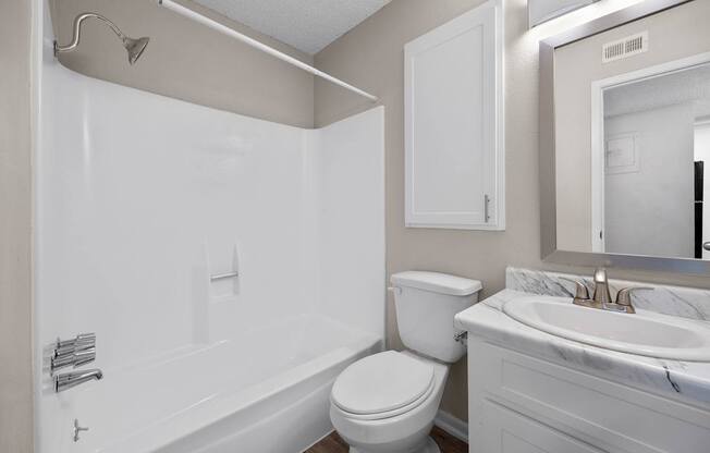 A white bathroom with a toilet, sink, and bathtub.