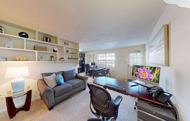 A well-lit room with a desk, chair, and a couch.