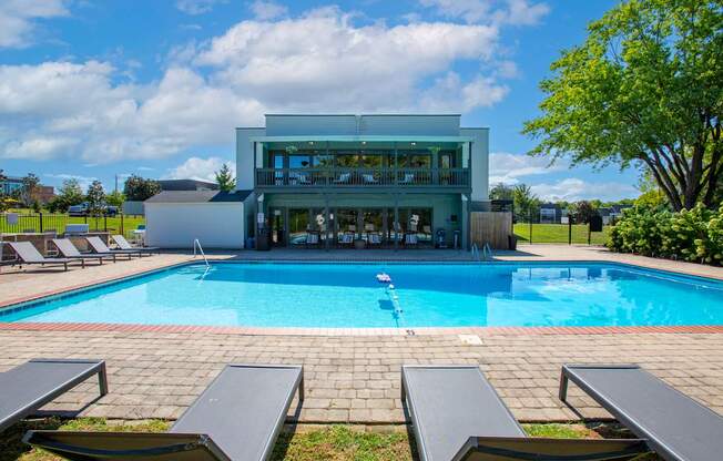 A swimming pool with lounge chairs and a building in the background.