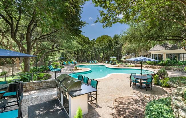 Surrounded by mature trees and seating areas, the poolside grilling station is ideal for outdoor dining and relaxing weekends.