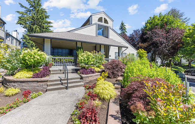 the front yard of a white house with a porch and landscaping