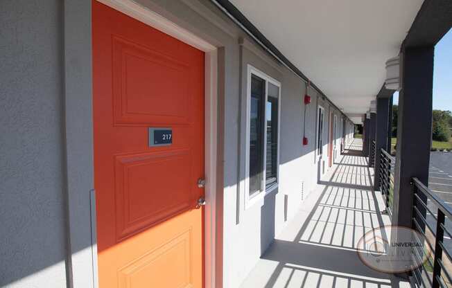 An orange door on a building with a porch.