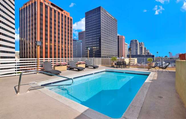 A swimming pool on a rooftop with a city skyline in the background.
