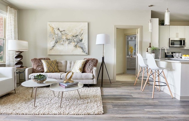 A living room with a white couch and a painting on the wall.