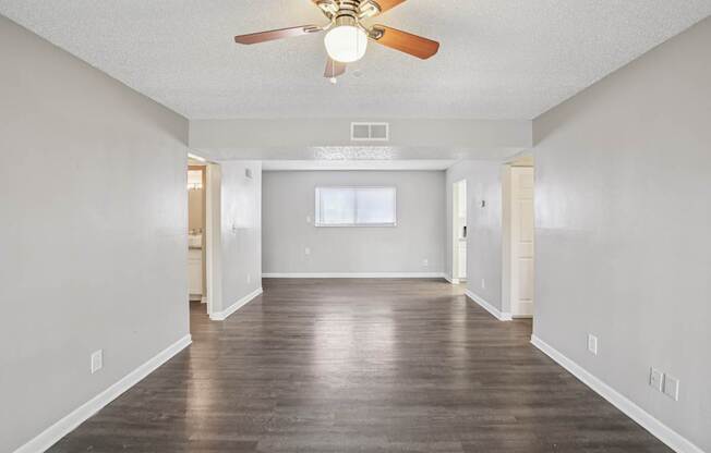 A room with a ceiling fan and wooden flooring.