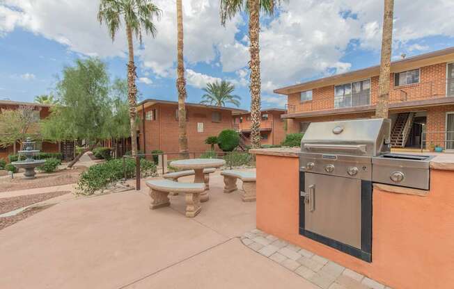 A patio with a table and chairs and a grill.