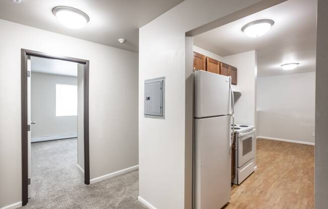 a room with a refrigerator and a stove and a door to a kitchen