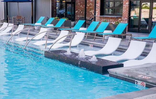 a swimming pool with white and blue chairs next to it