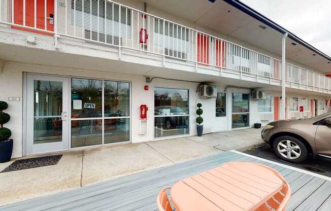 A building with red and white stripes on the balcony and a car parked in front.