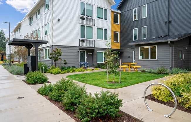 a view of a courtyard between two buildings with a yellow picnic table
